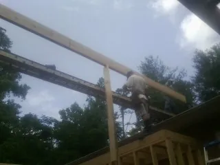 Carpenter setting a ridge beam over a new addition frame — Ice Dam Removal by Roofing Brothers in Leroy
