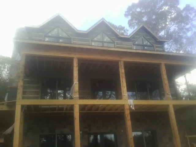 Dormers and porch framing on a large log home under construction — Roof Coating work by our crew in Leroy