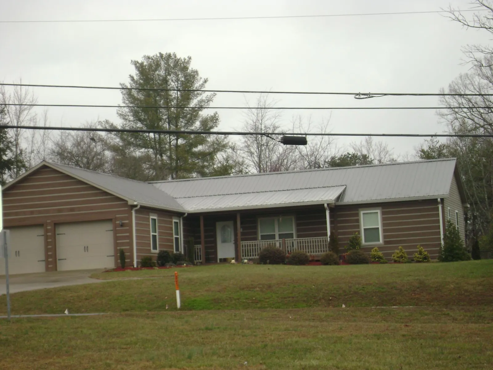 Gray metal roof on a log sided ranch home with a front porch in Leroy