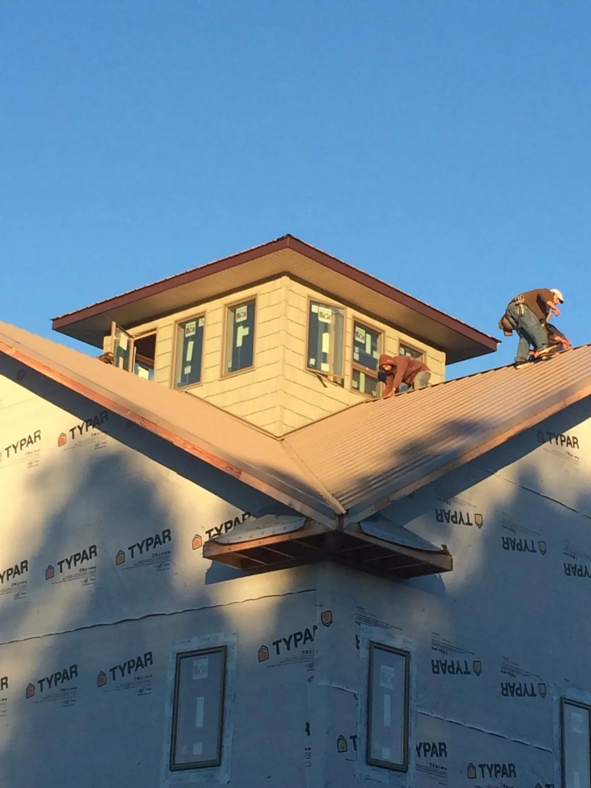 Roofers working around a rooftop cupola on a new metal roof at sunset — Roof Waterproofing in Leroy by Roofing Brothers